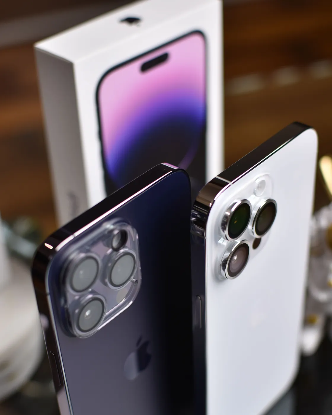 Due iPhone 14 Pro, viola scuro e argento, davanti alla loro scatola
